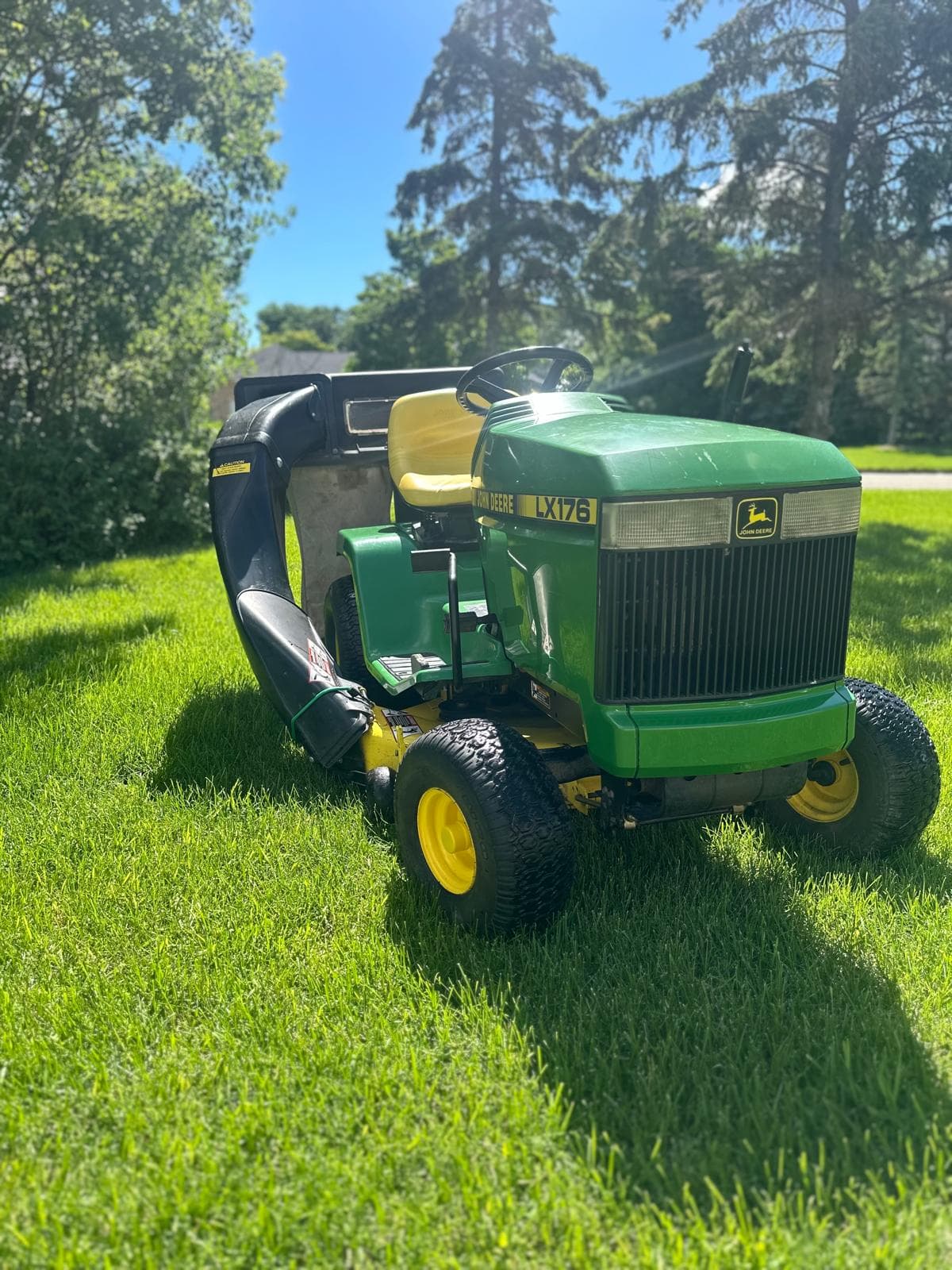 A green lawnmower on a well-maintained green lawn with freshly cut grass