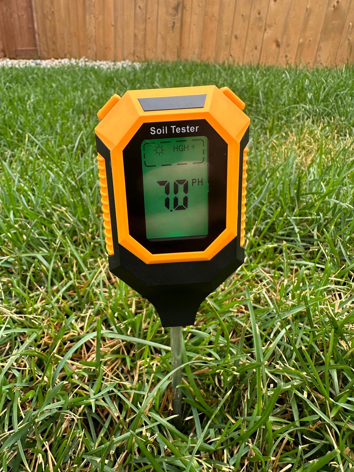 A soil Ph tester inserted in the soil on a lawn